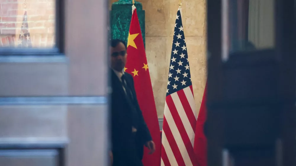 A man stands next to U.S. and China flags at Lancaster House, on the second day scheduled for trade talks between the U.S. and China, in London, Britain, June 10, 2025. REUTERS/Toby Melville