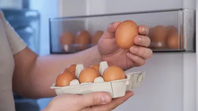Close up of a man putting fresh eggs into refrigerator.