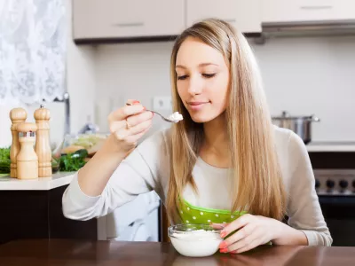 Blonde woman eating curd cheese in home kitchen / Foto: Jackf