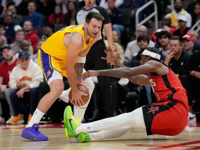 Houston Rockets' Tari Eason, right, falls while guarding Los Angeles Lakers' Luka Doncic during the first half of an NBA basketball game Monday, March 16, 2026, in Houston. (AP Photo/David J. Phillip)