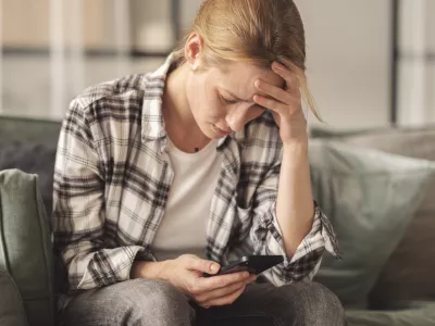 Woman reading some bad news on her smart phone, feeling sad and worried