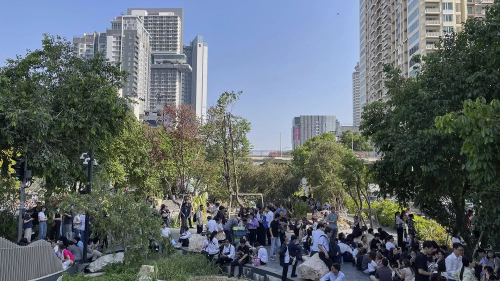 Office workers and residents who evacuated high-rise buildings after an earthquake wait in the shade along a canal in Bangkok, Friday, March 28, 2025. (AP Photo/Christie Hampton)