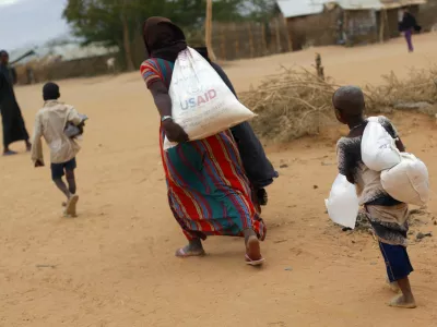 A newly arrived Somali family carry their supply of aid outside Dadaab, Eastern Kenya, 100 kms (60 miles) from the Somali border, Friday Aug. 5, 2011. Somali government troops opened fire Friday in Mogadishu on hungry civilians, killing at least seven people, as both groups made a grab for food at a U.N. distribution site in the capital of this famine-stricken country, witnesses said. The drought and famine in the horn of Africa has killed more than 29,000 children under the age of 5 in the last 90 days in southern Somalia alone, according to U.S. estimates. The U.N. says 640,000 Somali children are acutely malnourished, suggesting the death toll of small children will rise. (AP Photo/Jerome Delay)