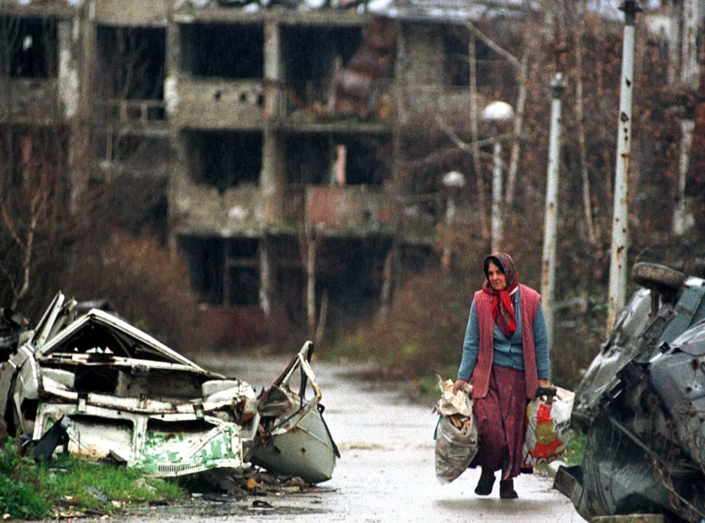 An elderly woman carries her belongings November 22 in Sarajevo's war shattered airport settlement. The mandate of the Organisation for Security and Cooperation in Europe (OSCE) mission in Bosnia has been extended for another year - until Dec. 31, 1997. - PBEAHUMYFCR
