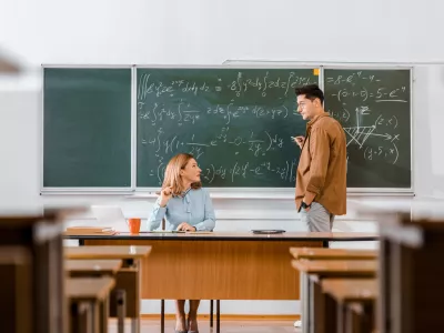 male student looking at female teacher and solving equations during lesson in classroom / Foto: Lightfieldstudios