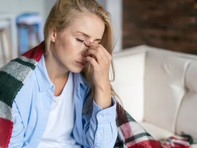 Fatigue and upset woman touching nose bridge feeling eye strain or headache, trying to relieve pain. Sick and exhausted female spending day at home. Depressed lady feeling weary dizzy