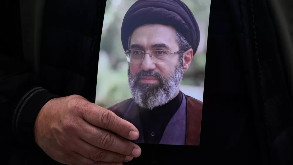 A man holds a poster of the Iranian Supreme Leader Ayatollah Mojtaba Khamenei during the funeral procession of Gen. Ali Mohammad Naeini, a spokesperson for Iran's paramilitary Revolutionary Guard and one of his comrades Amir Hossein Bidi in Tehran, Iran, Saturday, March 21, 2026. (AP Photo/Vahid Salemi)