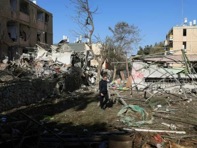 A man walks near debris from damage following a night of Iranian missile strikes which injured dozens of Israelis, amid the U.S.-Israel conflict with Iran, in Dimona, southern Israel, March 22, 2026. REUTERS/Ronen Zvulun