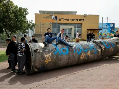 Children and teenagers play with a part of a missile that landed in the playground of an elementary school last night, amid the U.S.-Israel conflict with Iran, in the Israeli settlement Peduel of the Israel-occupied West Bank, March 23, 2026. REUTERS/Amir Cohen   TPX IMAGES OF THE DAY