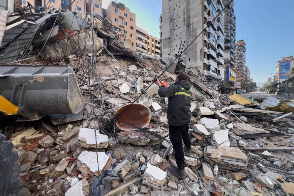 A civil defense worker cuts a power cable in front of a destroyed building that was hit by an Israeli airstrike in Dahiyeh, Beirut's southern suburbs, Lebanon, Tuesday, March 24, 2026. (AP Photo/Hussein Malla)