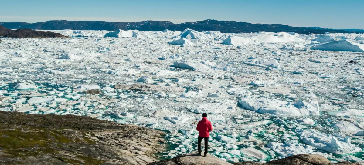 Travel in arctic landscape nature with icebergs - Greenland tourist man explorer - tourist person looking at amazing view of Greenland icefjord - aerial drone image. Man by ice and iceberg, Ilulissat. / Foto: Maridav