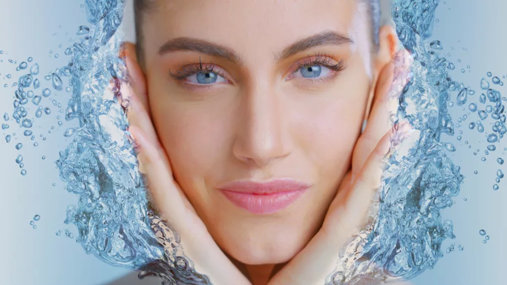 Portrait of woman with beautiful face and perfect skin just cleaned from impurities touching it gently with 3d water hands to show how soft, smooth and pure it is.