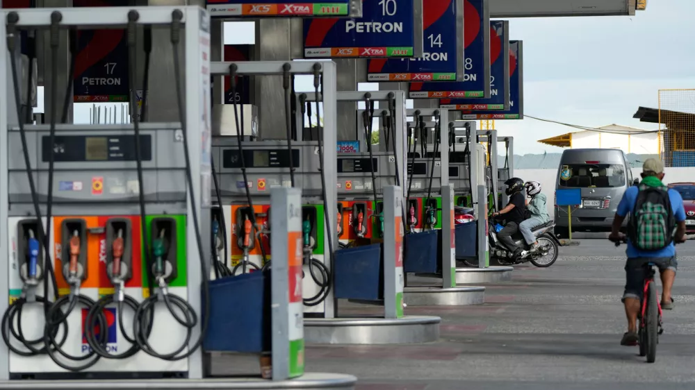 A motorcycle rider enters a gasoline station while a bicycle passes by on Wednesday, March 25, 2026, in Paranaque city, Philippines. (AP Photo/Aaron Favila)