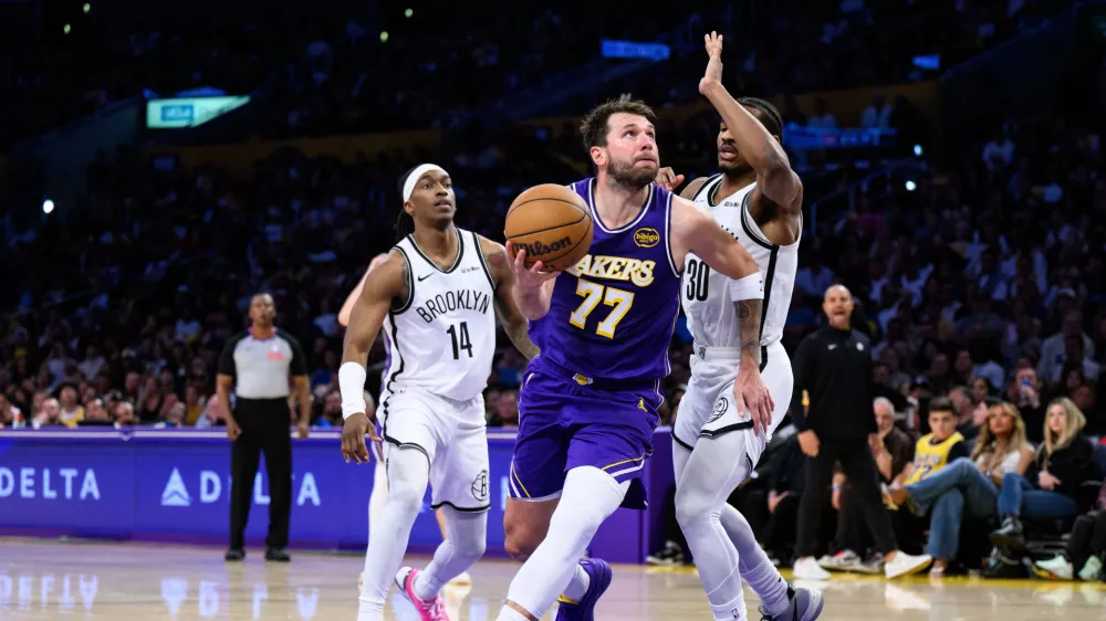 Mar 27, 2026; Los Angeles, California, USA; Los Angeles Lakers guard Luka Doncic (77) drives against Brooklyn Nets guards Ochai Agbaji (30) and Terance Mann (14) during the second half at Crypto.com Arena. Mandatory Credit: William Liang-Imagn Images