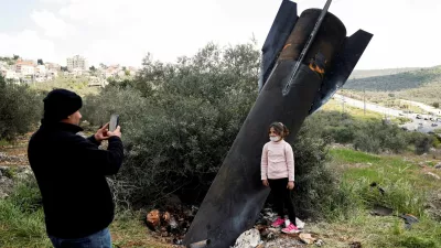 FILE PHOTO: A girl poses for a picture next to the remnants of a missile stuck in the ground found in Kifl Haris village, near Nablus in the Israeli-occupied West Bank, March 24, 2026. REUTERS/Mohammed Torokman/File Photo