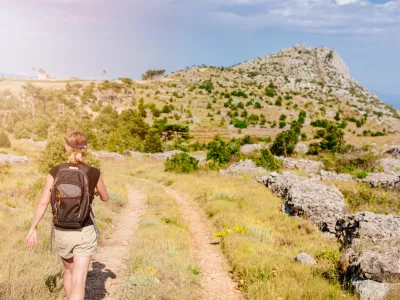 Young woman with backpack at mountain trail. Sveti Nikola mount, Hvar Island, Croatia