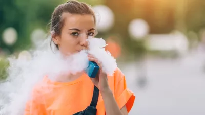Pretty young girl vape popular ecig gadget,vaping device.Happy brunette vaper girl with e-cig.Portrait of smoker female model with electronic cigarette vaporizer.Ejuice vaping with fruit flavor liquid
