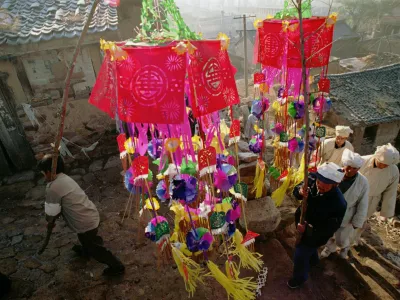 A funeral procession passes through Xin Village in China's Shanxi province, led by family members carrying paper decorations Sunday November 10, 1996. Though elaborate funerals are now rare in China's cities, in rural areas old traditions are still followed. Though China's government has made cremation compulsory, to save valuable land space, in rural areas the dead are often buried on the land in accordance with tradition. (AP Photo)