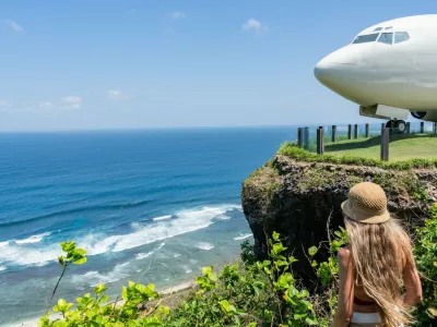 Blonde tourist admiring repurposed boeing 737 airplane on a cliff overlooking the indian ocean in bali,Image: 1001085464, License: Royalty-free, Restrictions:, Model Release: yes