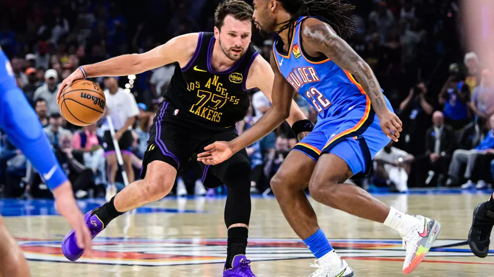 Los Angeles Lakers forward/guard Luka Dončić (77) drives against Oklahoma City Thunder guard Cason Wallace (22) during the first half of an NBA basketball game Thursday, April. 2, 2026, in Oklahoma City. (AP Photo/Gerald Leong)