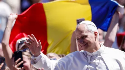 Faithful hold a Romanian flag as Pope Leo XIV waves from the popemobile after delivering his "Urbi et Orbi" (To the city and the world) message, on Easter Sunday, at the Vatican, April 5, 2026. REUTERS/Remo Casilli