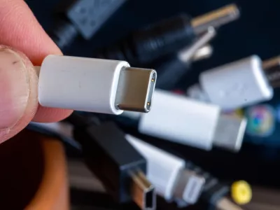 04 October 2022, Mecklenburg-Western Pomerania, Schwerin: A charging cable with USB-C connector is held next to a bundle of different connecting cables. Mobile phones and other electronic devices in the European Union will have to have standardized charging equipment starting from 2024, under legislation approved by the European Parliament on Tuesday. Photo: Jens B&uuml;ttner/dpa