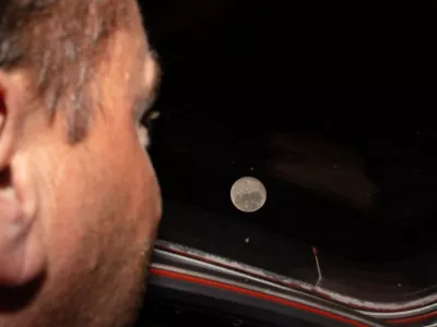 In this photo provided by NASA, Artemis II commander and NASA astronaut Reid Wiseman looks out one of the Orion spacecraft's main cabin windows at the Moon ahead of the crew's lunar flyby on April 6, 2026. (NASA via AP)