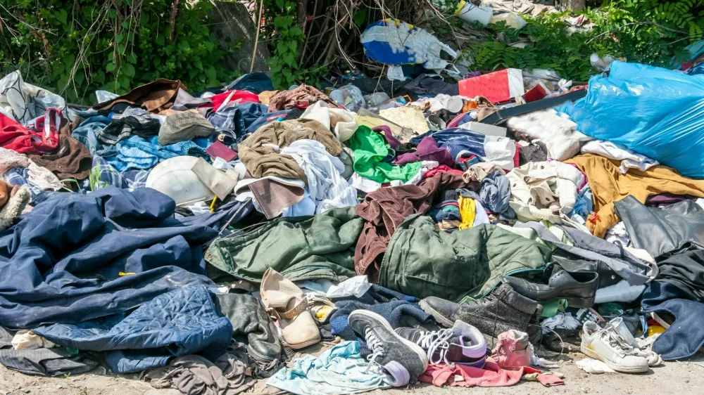 Pile of old clothes and shoes dumped on the grass as junk and garbage, littering and polluting the environment / Foto: Srdjanns74