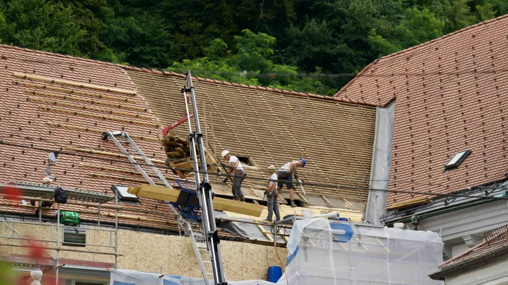 Roofers doing renovation work on rooftop at the old town of City of Ljubljana on a cloudy summer day. Photo taken August 9th, 2023, Ljubljana, Slovenia. / Foto: Michael Derrer Fuchs