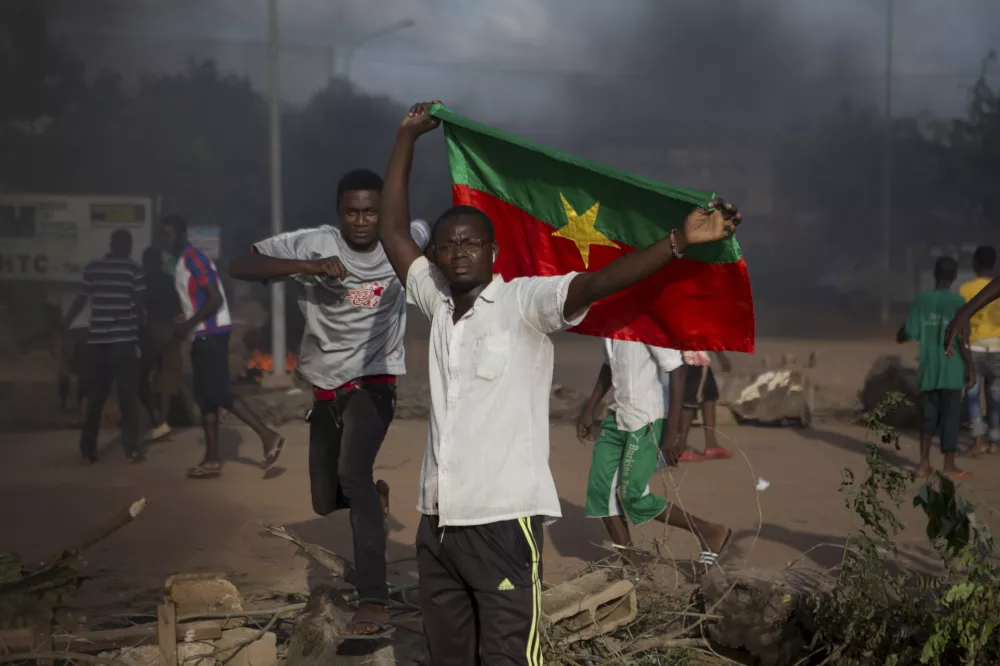 An anti-coup protester holds a Burkinabe flag in Ouagadougou, Burkina Faso, September 18, 2015. Leaders of a coup in Burkina Faso said on Friday they had freed the president and reopened borders, in an apparent olive branch to mediators and protesters who rallied in the capital and other cities against the putsch. REUTERS/Joe Penney   TPX IMAGES OF THE DAY   - RTS1SZD