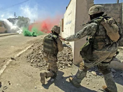 U.S. marines from the I Marine Expeditionary Force take their position near colored smokes to cover their movement during a firefight with insurgents in Ramadi, 100 km (60 miles), west of Baghdad, in this photo taken June 15, 2006 and released June 17, 2006.  NO SALES  NO ARCHIVES.  FOR EDITORIAL USE ONLY     REUTERS/Petty Officer 2nd Class Samuel C. Peterson/Handout  (IRAQ)