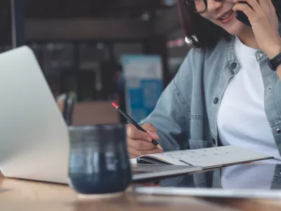 Smart asian business woman talking on mobile phone during planning work schedule with laptop computer and digital tablet on table at coffee shop. Happy businesswoman online working from cafe, business casual