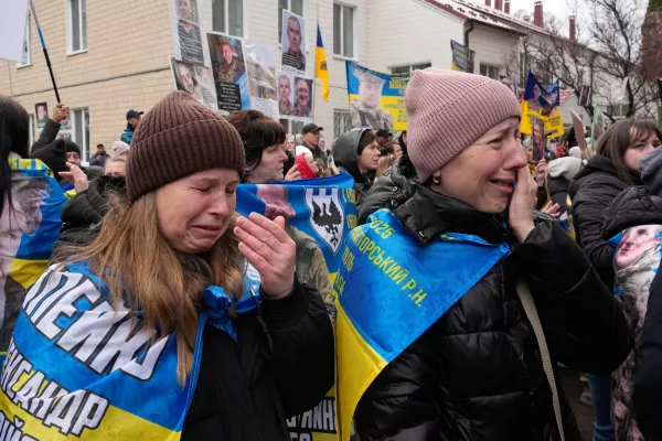 People cry as they hold hold photos of their missed relatives as Ukrainian soldiers return from captivity during a POW exchange between Russia and Ukraine in Chernyhiv region, Ukraine, Saturday, April 11, 2026. (AP Photo/Efrem Lukatsky)