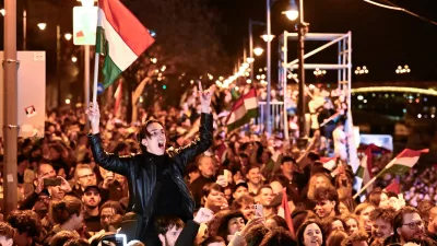 A man waves a Hungarian flag as he celebrates in the streets after the announcement of partial results of the Hungarian parliamentary election in Budapest, Hungary, Sunday, April 12, 2026. (AP Photo/Denes Erdos)