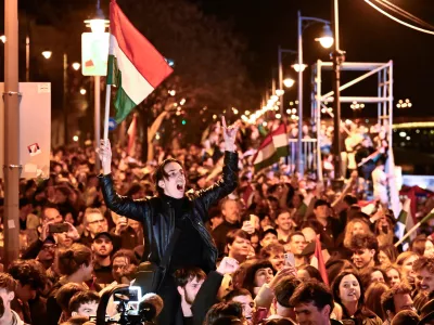 A man waves a Hungarian flag as he celebrates in the streets after the announcement of partial results of the Hungarian parliamentary election in Budapest, Hungary, Sunday, April 12, 2026. (AP Photo/Denes Erdos)