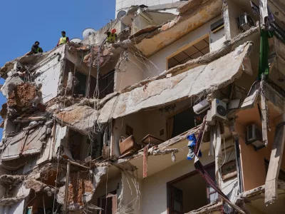 Workers remove the rubble as rescuers keep searching for a missing woman and girl at a destroyed building that was hit on April 8, in an Israeli airstrike in Beirut, Lebanon, Monday, April 13, 2026. (AP Photo/Hussein Malla)