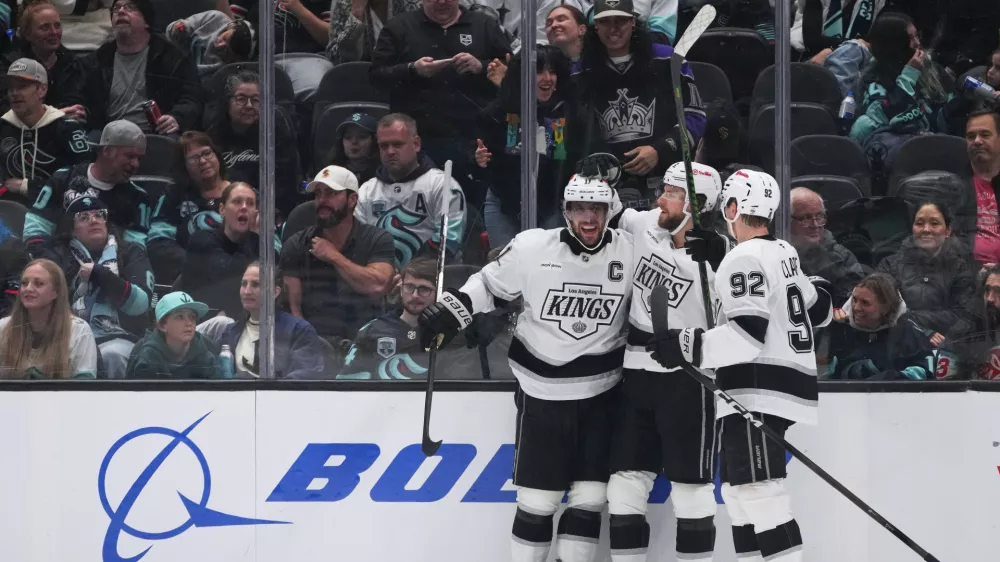 Los Angeles Kings right wing Adrian Kempe, center, celebrates his goal with center Anze Kopitar, left, and defenseman Brandt Clarke, right, against the Seattle Kraken during the third period of an NHL hockey game Monday, April 13, 2026, in Seattle. (AP Photo/Lindsey Wasson)