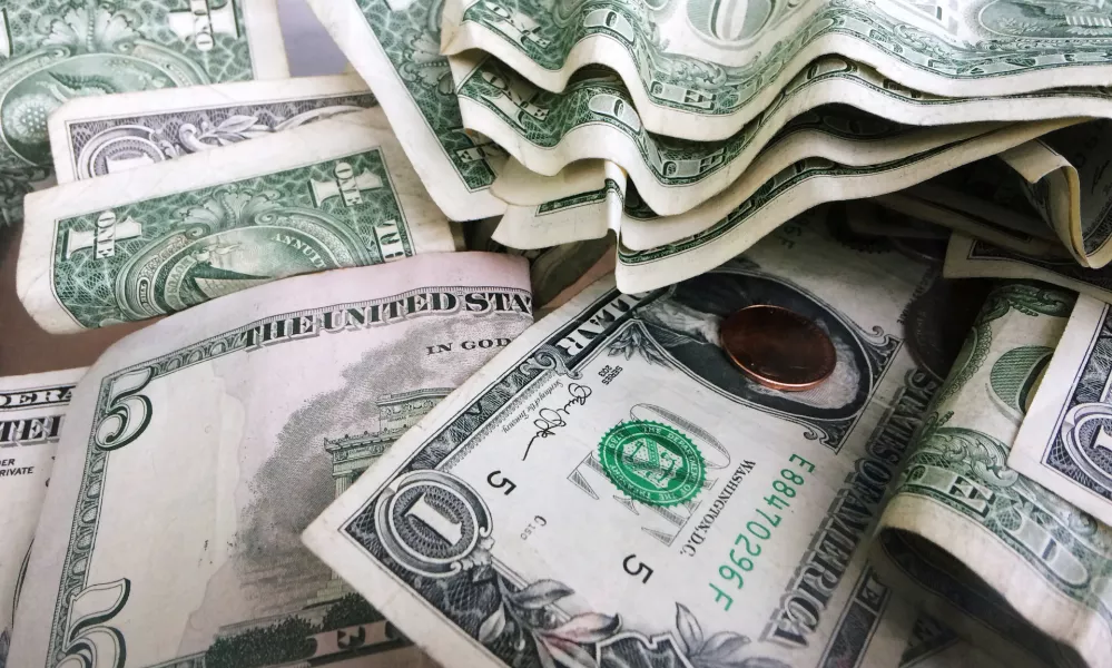 FILE- This Sept. 6, 2017, file photo shows a tip jar with one dollar and five dollar bills and a penny in New York. Millions of Americans deal with food, housing and general financial insecurity every year. Getting help can be tedious and time consuming, especially if you're facing language barriers, don't have reliable internet access or simply don't have the bandwidth because you're caring and providing for your family. Nonprofit organizations like 211.org and the National Low Income Housing Coalition can help you navigate the maze of local, state and federal programs available. (AP Photo/Mark Lennihan, File)