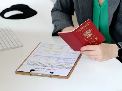 Top view close up of a caucasian woman filling out visa application documents with a Russian passport on a office table,Image: 878148738, License: Royalty-free, Restrictions:, Model Release: no