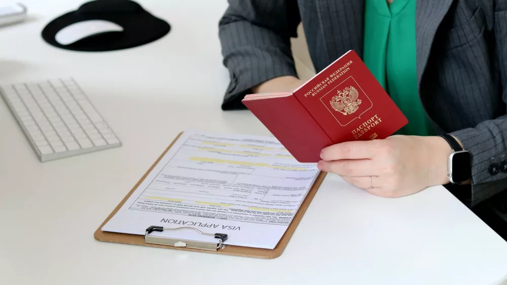 Top view close up of a caucasian woman filling out visa application documents with a Russian passport on a office table,Image: 878148738, License: Royalty-free, Restrictions:, Model Release: no