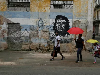 People walk past an image of late revolutionary Ernesto "Che" Guevara painted on a wall, as Cuba reconnected its electrical grid across much of the island, according to the Energy and Mines Ministry, following a nationwide blackout that left about 10 million people without electricity, in Havana, Cuba, March 17, 2026. REUTERS/Norlys Perez