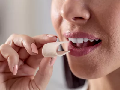 Detail of a woman putting a folded chewing gum into her mouth. / Foto: Marianvejcik