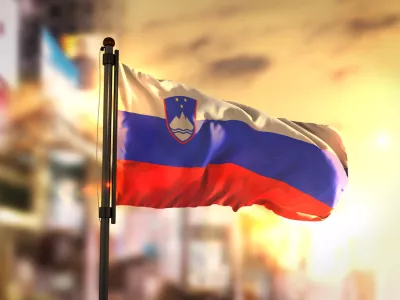 Slovenia Flag Against City Blurred Background At Sunrise Backlight