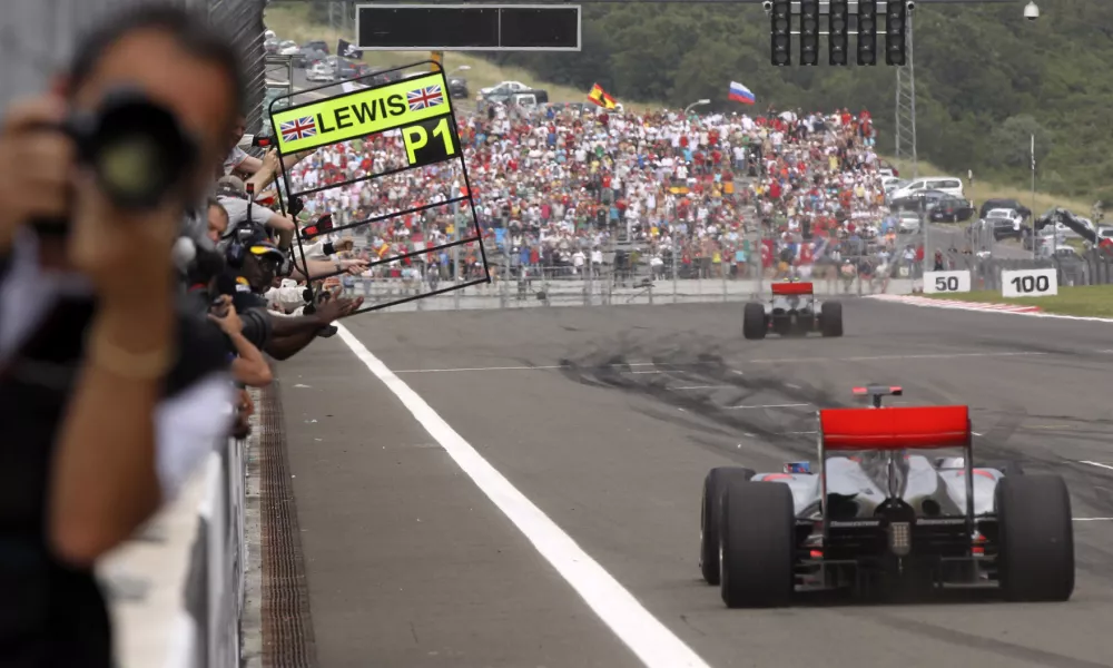 McLaren Mercedes driver Lewis Hamilton of Britain is seen in background after crossing the finish line to win the Turkish Formula One Grand Prix at the Istanbul Park circuit racetrack, in Istanbul, Turkey, Sunday, May 30, 2010. In foreground is seen second place McLaren Mercedes driver Jenson Button of Britain. (AP Photo/Thanassis Stavrakis)