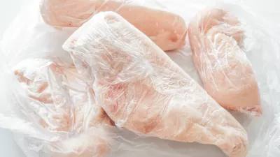 Frozen chicken breast in food plastic wrap or cling film. Photo can be used for how to wrap meat for freezer concept.
