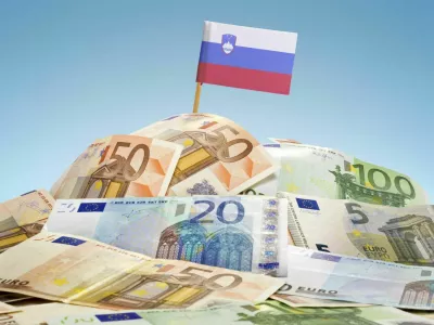 The national flag of Slovenia sticking in a pile of mixed european banknotes.(series) / Foto: Eyegelb