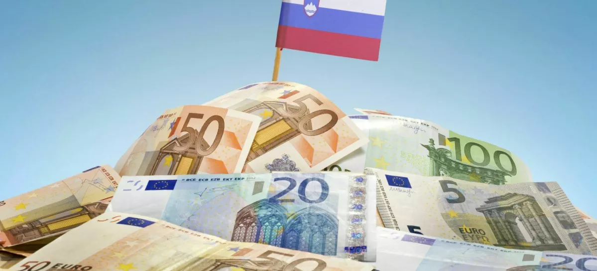 The national flag of Slovenia sticking in a pile of mixed european banknotes.(series) / Foto: Eyegelb