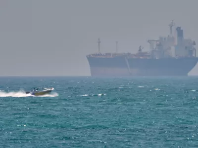 A boat sails past a tanker anchored on the Strait of Hormuz off the coast Qeshm island, Iran, Saturday, April 18, 2026. (AP Photo/Asghar Besharati)