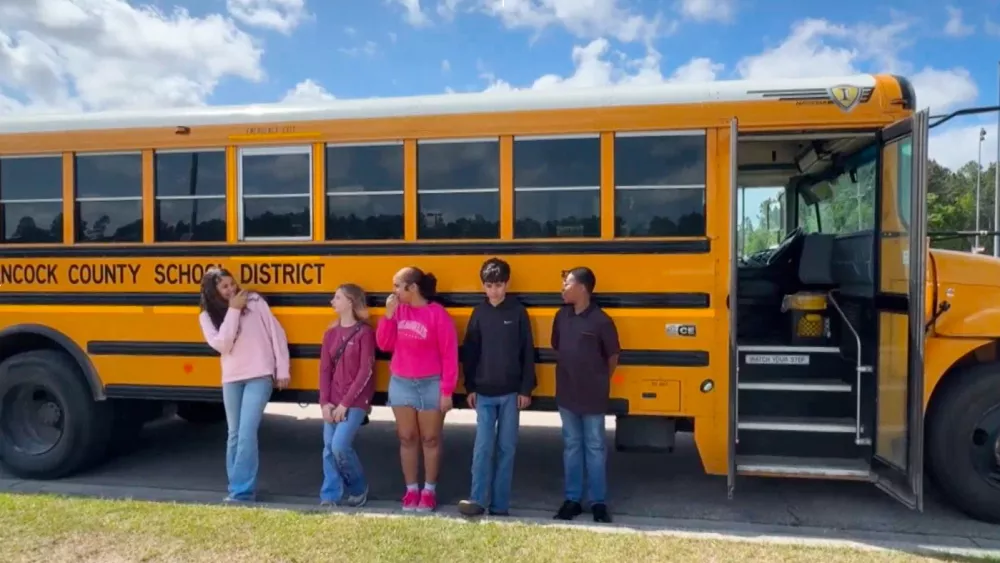 Five middle school students, who helped stop a bus after their driver passed out during a medical emergency, stand outside a bus in Hancock County, Miss., on Thursday, April 23, 2026. (WLOX via AP)