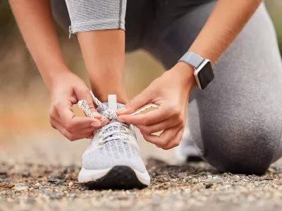 Shoes, fitness and exercise with a sports woman tying her laces before training, running or a workout. Hands, health and cardio with a female runner or athlete getting ready for an endurance run